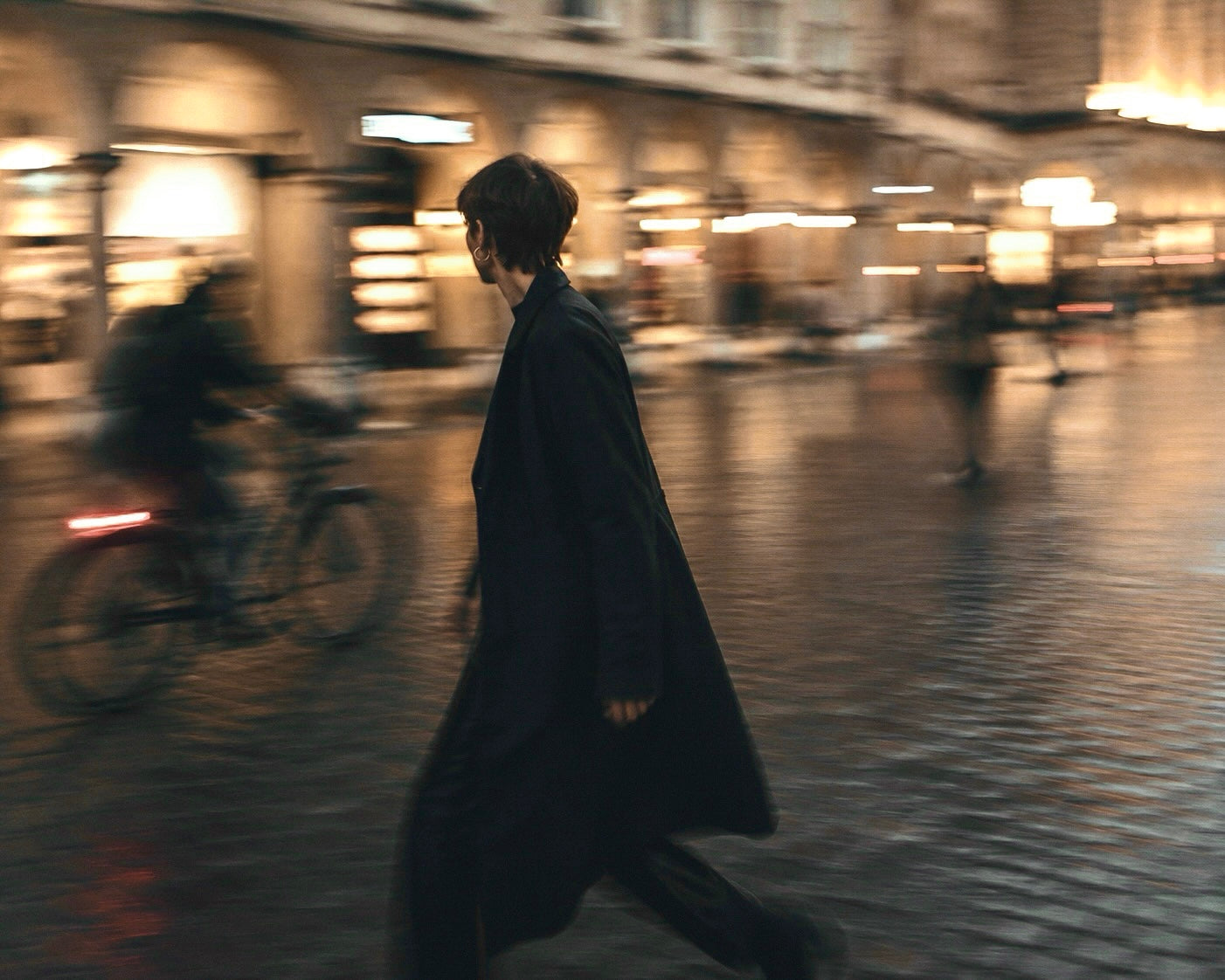 A figure crossing a city street at dusk